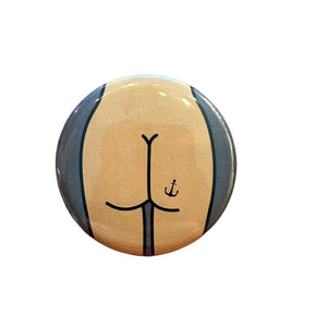 Round button with a stylized design of a butt with an anchor tattoo.