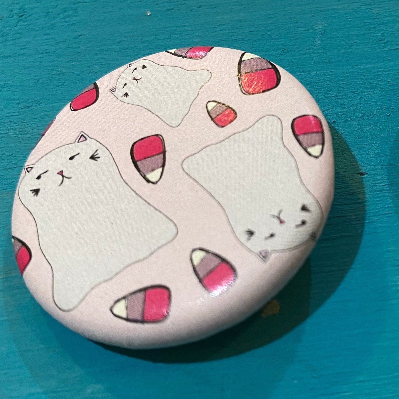 Round button with cat design on a blue surface
