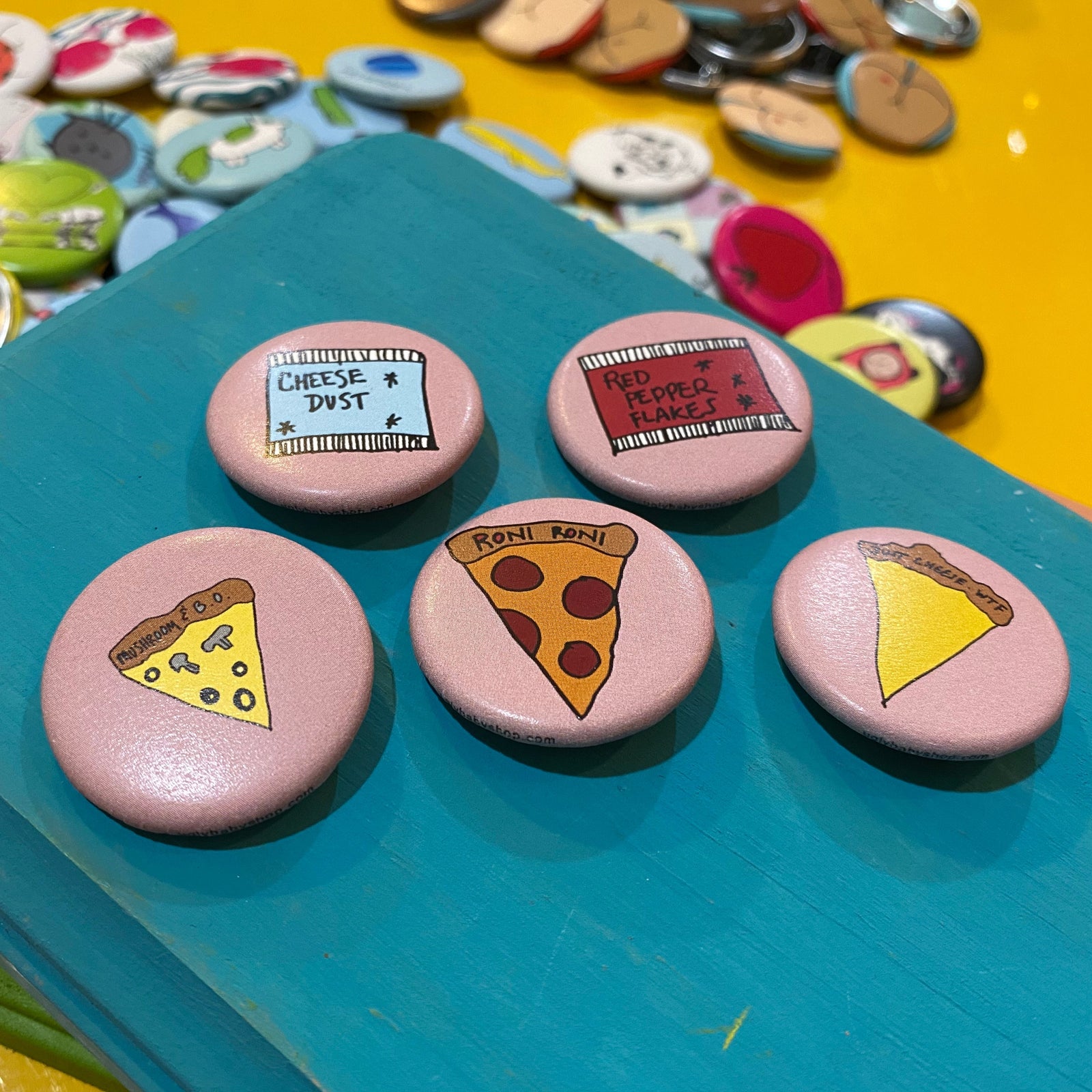 Collection of pizza-themed buttons on a blue surface with a yellow background