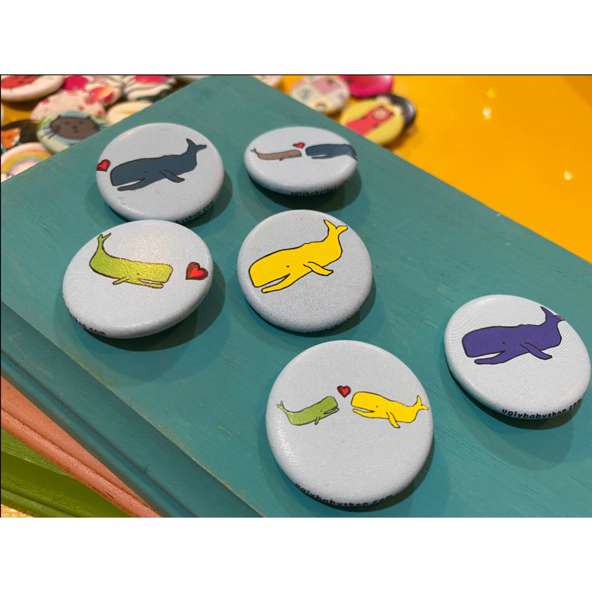 Colorful whale-themed buttons on a green surface with a colorful background