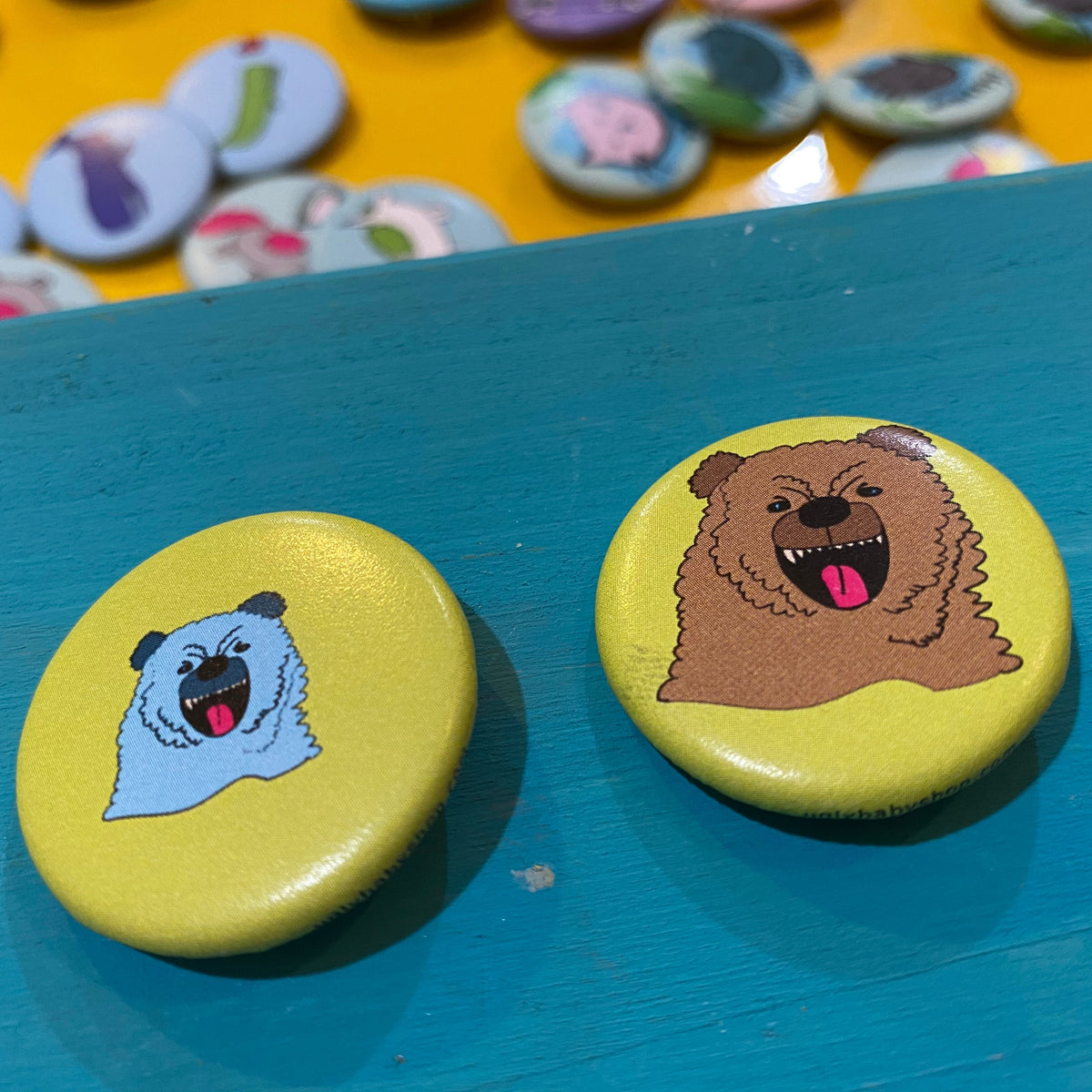 Two colorful buttons with animal illustrations on a blue surface, with more buttons in the background.