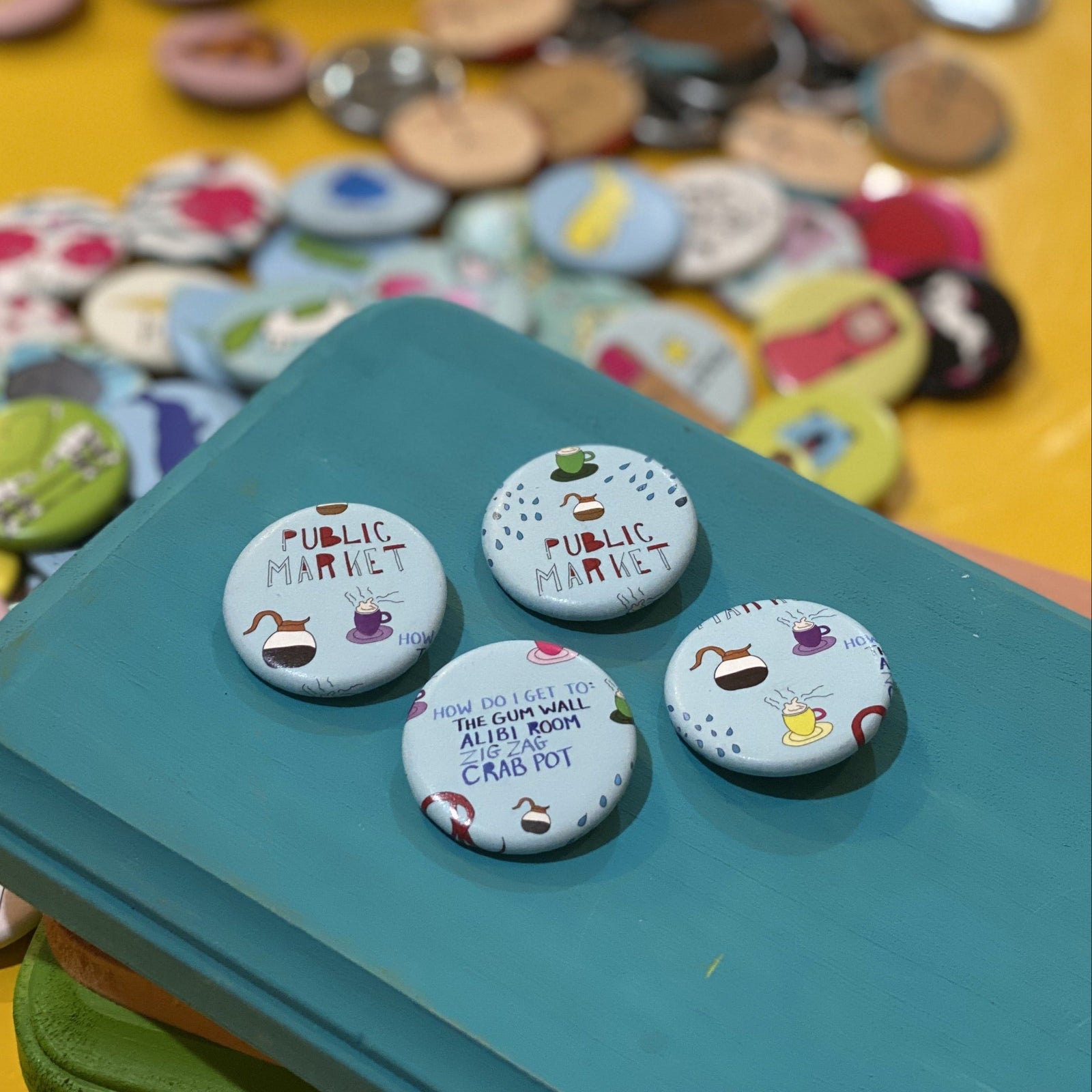 Four round buttons with 'Public Market' text on a teal surface, with a colorful assortment of buttons in the background.