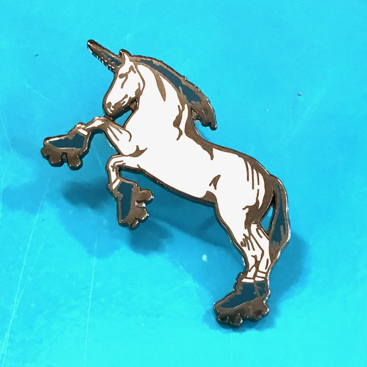 A unicorn wearing roller skates. She has an aqua mane, horn and roller skates. 