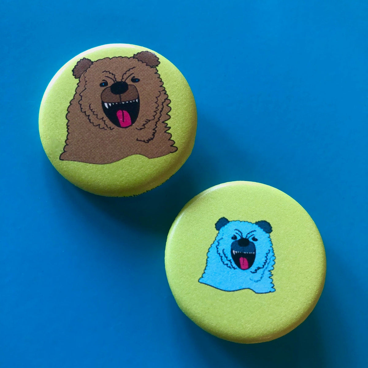 Two green buttons with drawings of bears on them-one brown and one blue. 