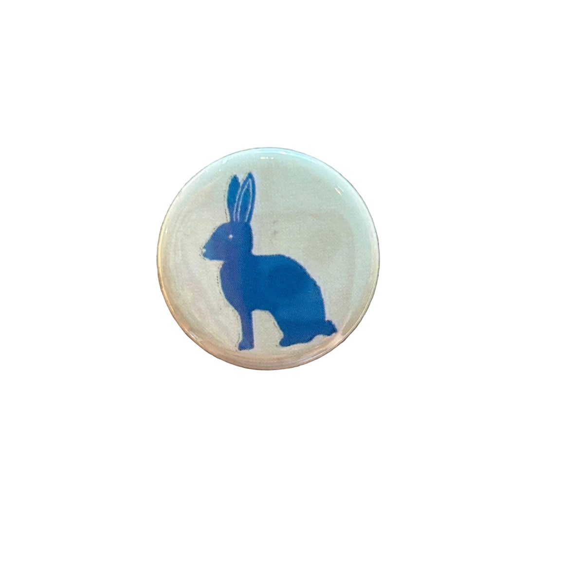 Round white magnet with a blue rabbit drawing on it. 