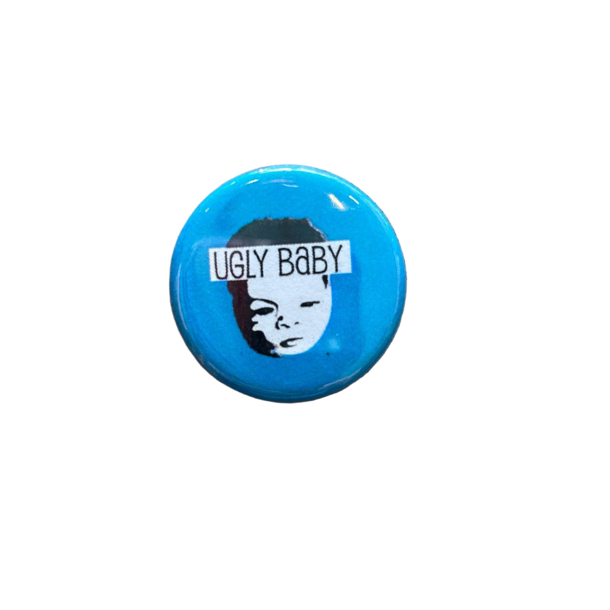 A round blue magnet with a black and white face and text that says "UGLY BABY"