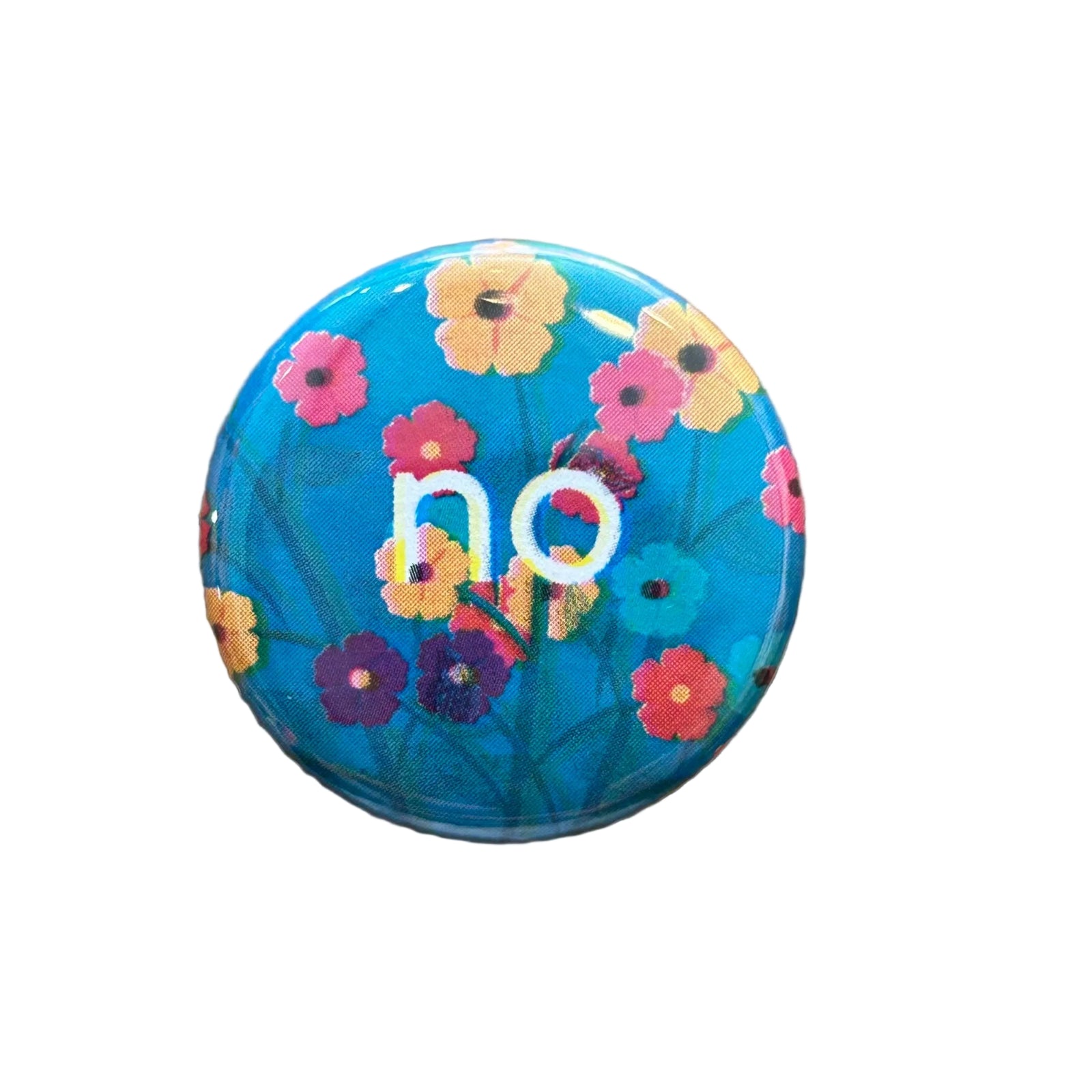 A round blue floral magnet with text that says "no" on a white backdrop. 