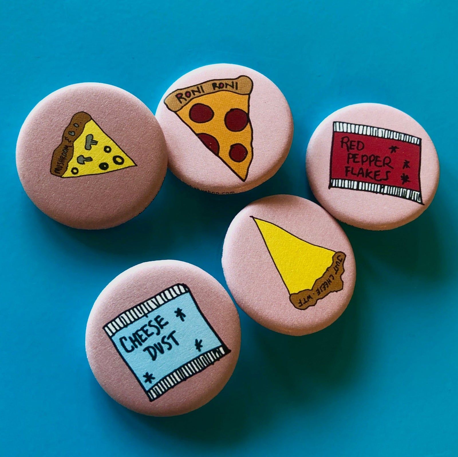 A grouping of pink magnets featuring illustrations of pizza slices, cheese dust, and red pepper flakes against a blue background. 