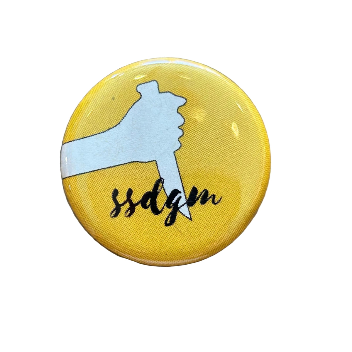 A round yellow magnet with the white silhouette of a hand holding a knife and script that says "ssdgm"