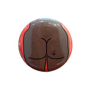 Round magnet with a cartoon illustration of a butt against a white background