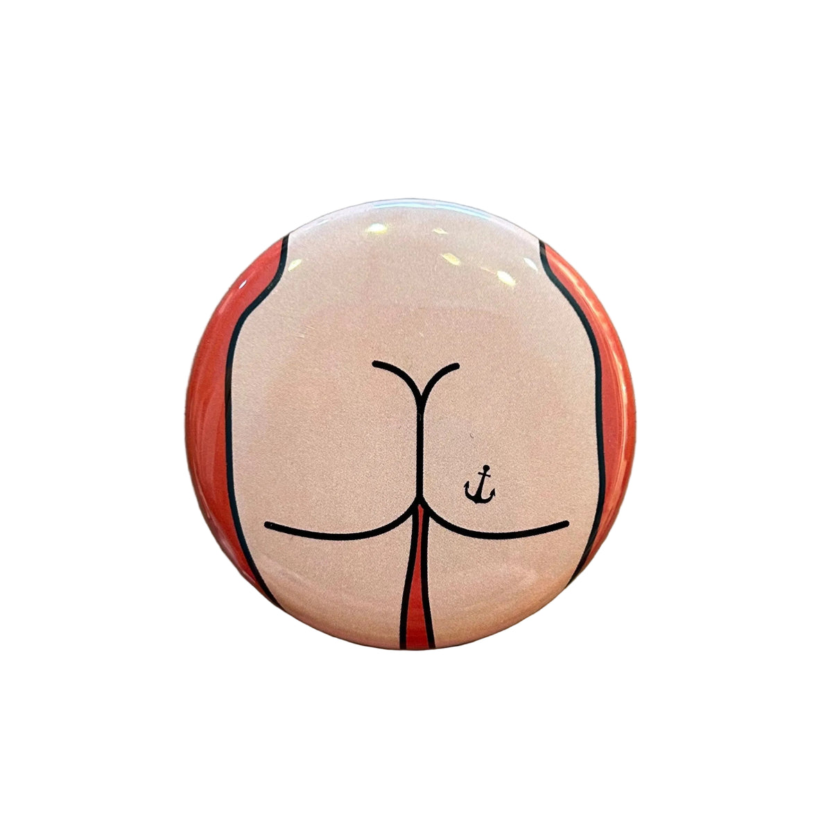Round magnet with a cartoon butt design against a white background. 