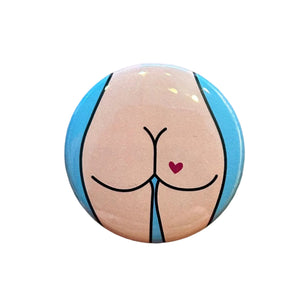 Round magnet with a cartoon butt illustration against a white background. 