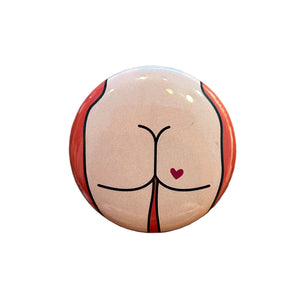 Round magnet with a cartoon illustration of a butt against a white background