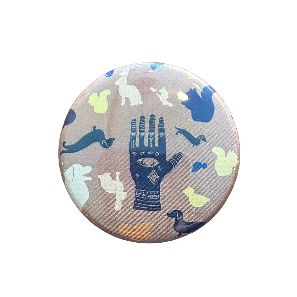 Round brown magnet with an illustration of a hand with an eye in the middle and various animals around it. 