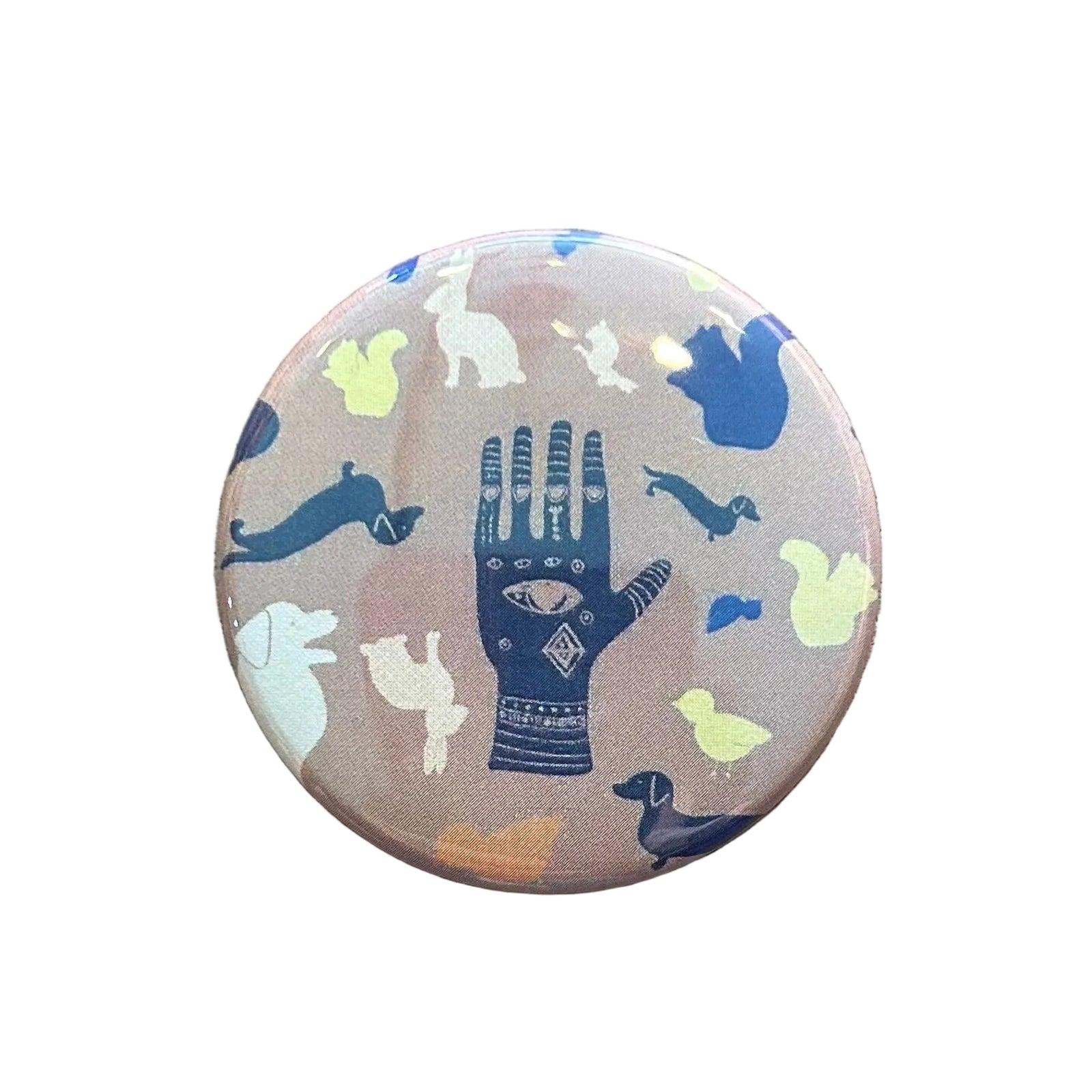 Round brown magnet with an illustration of a hand with an eye in the middle and various animals around it. 