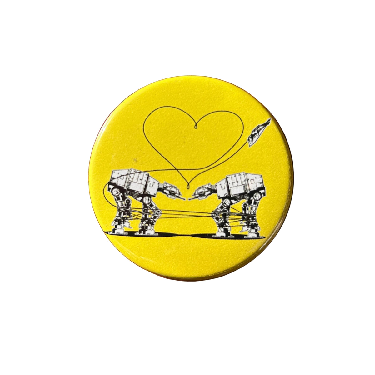 Round yellow magnet with an illustration of two AT-ATs from Star Wars with a heart  above them. 