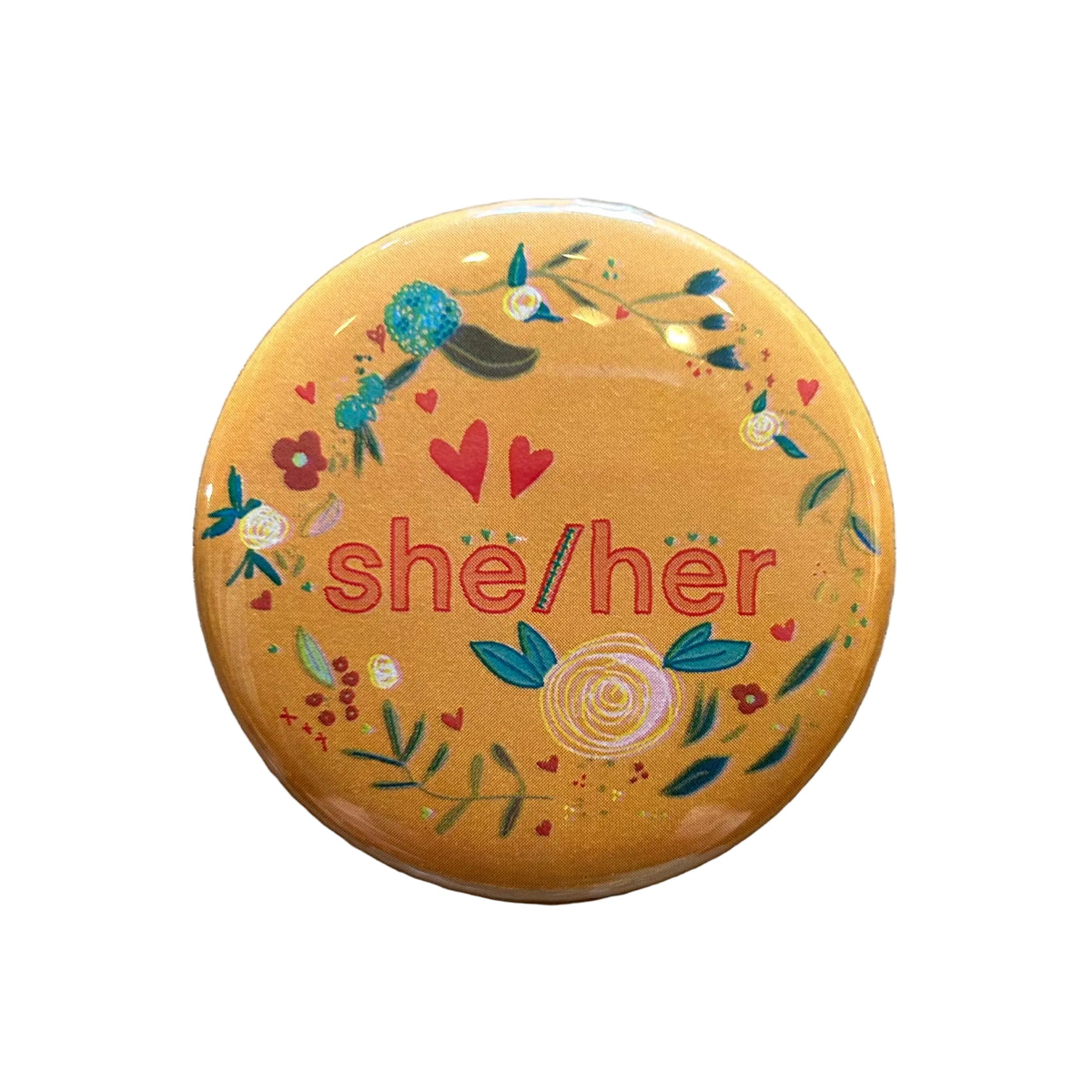 Round orange magnet with a floral border and text in the middle that says "she/her"