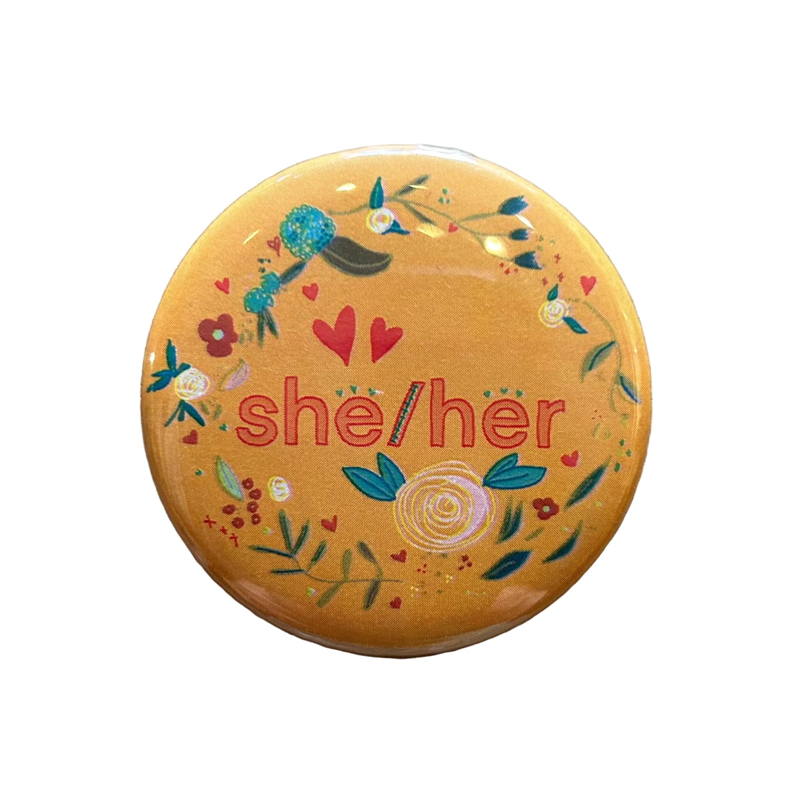 Round orange magnet with a floral border and text in the middle that says "she/her"