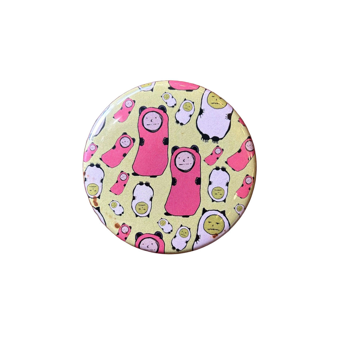 Round magnet with a design of pink and green cartoon characters. 