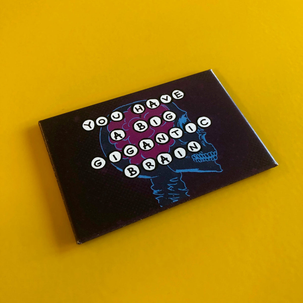 Dark blue rectangular magnet with an illustration of a skeleton with a brain inside of it and text that reads "YOU HAVE A BIG GIGANTIC BRAIN"