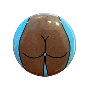 Round mirror with a cartoon illustration of a butt on the back. 