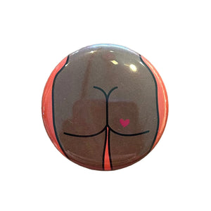 Round mirror with a cartoon illustration of a butt with a heart tattoo on the back