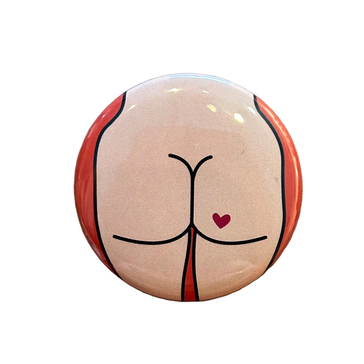 Round mirror with  a design of a cartoon butt with a heart tattoo on the back. 