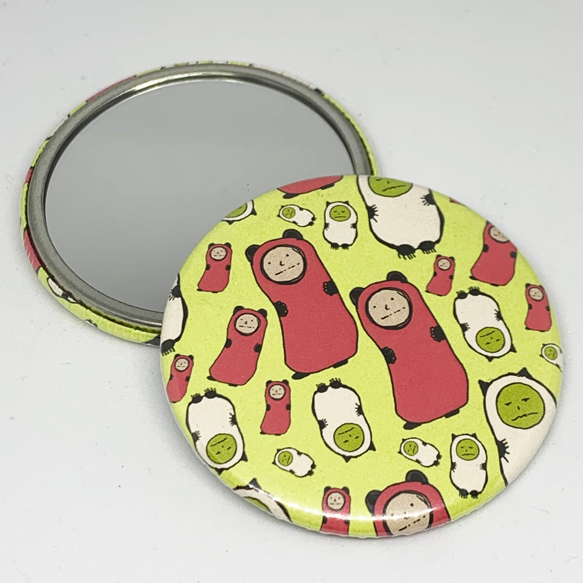 Round green mirror with cartoon illustrations of frowning characters.