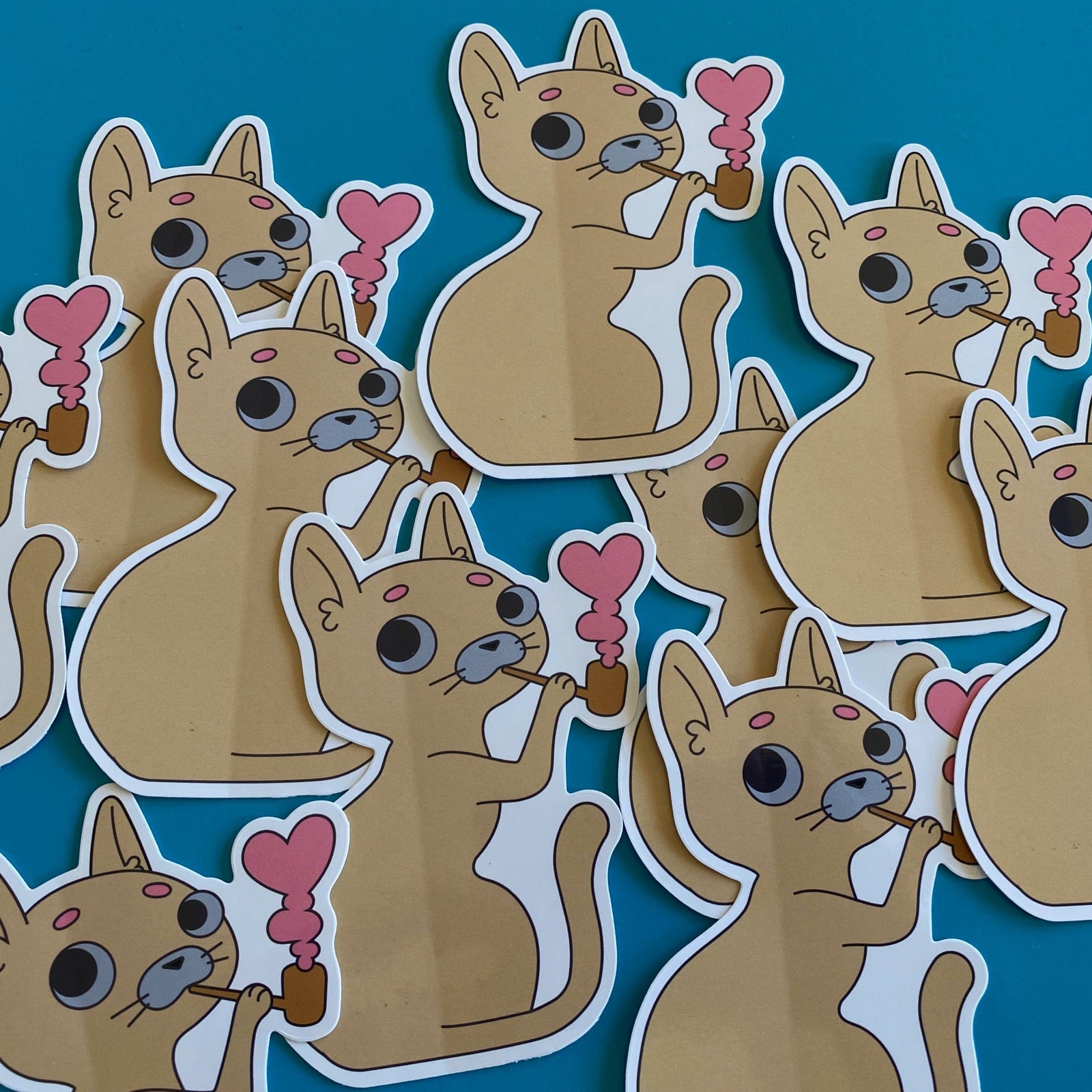 Stickers of cartoon cats holding corn cob pipes on a blue background