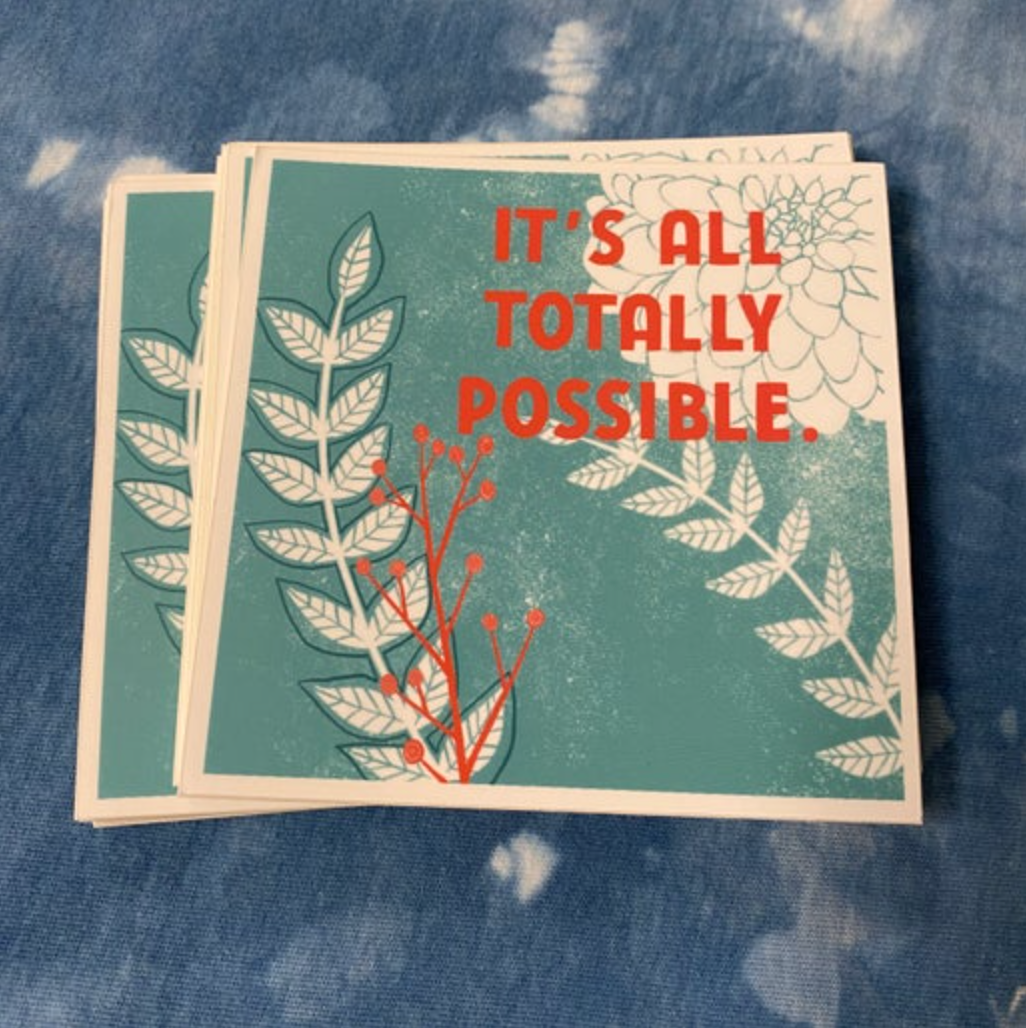 Sticker with floral design and 'It's all totally possible' text on a blue textured background