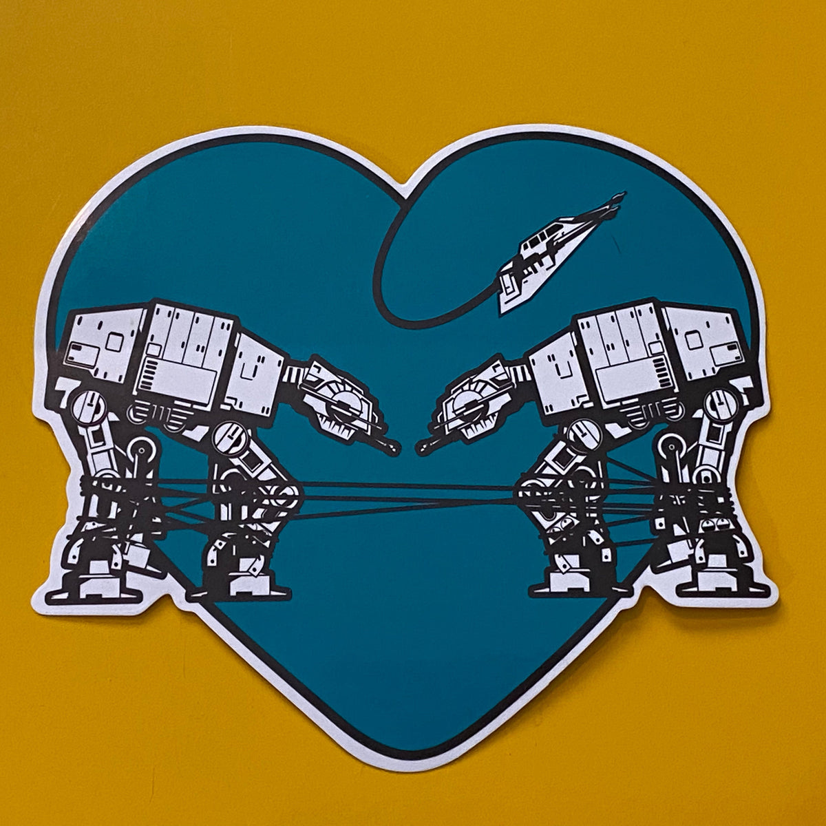 Heart-shaped sticker with two robots  on a yellow background