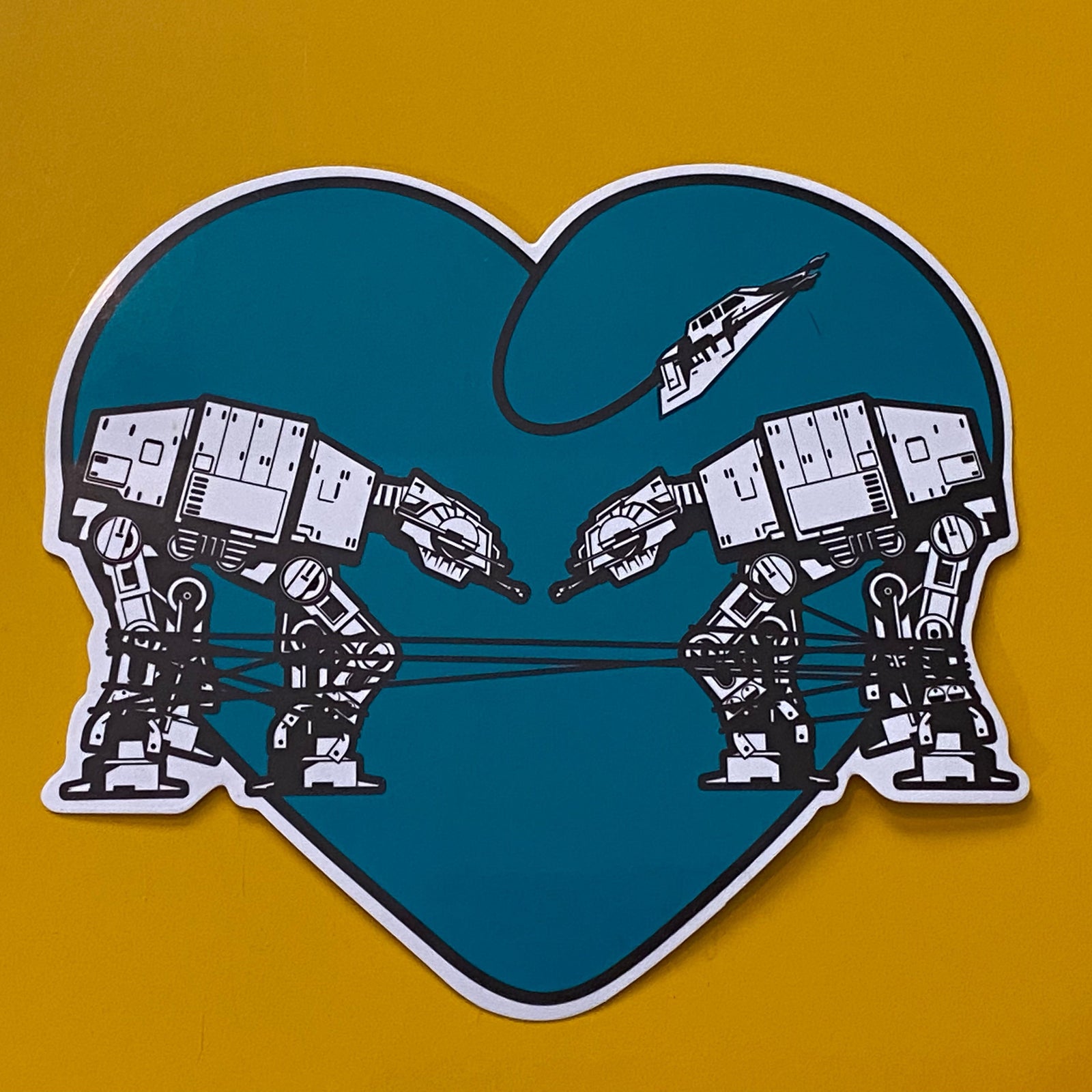 Heart-shaped sticker with two robots  on a yellow background