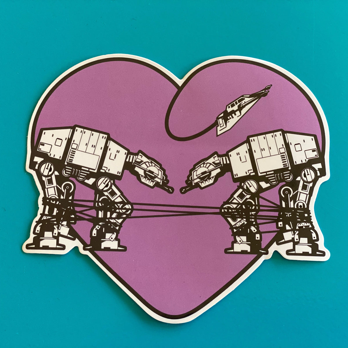 Sticker of two robots inside a purple heart shape on a teal background