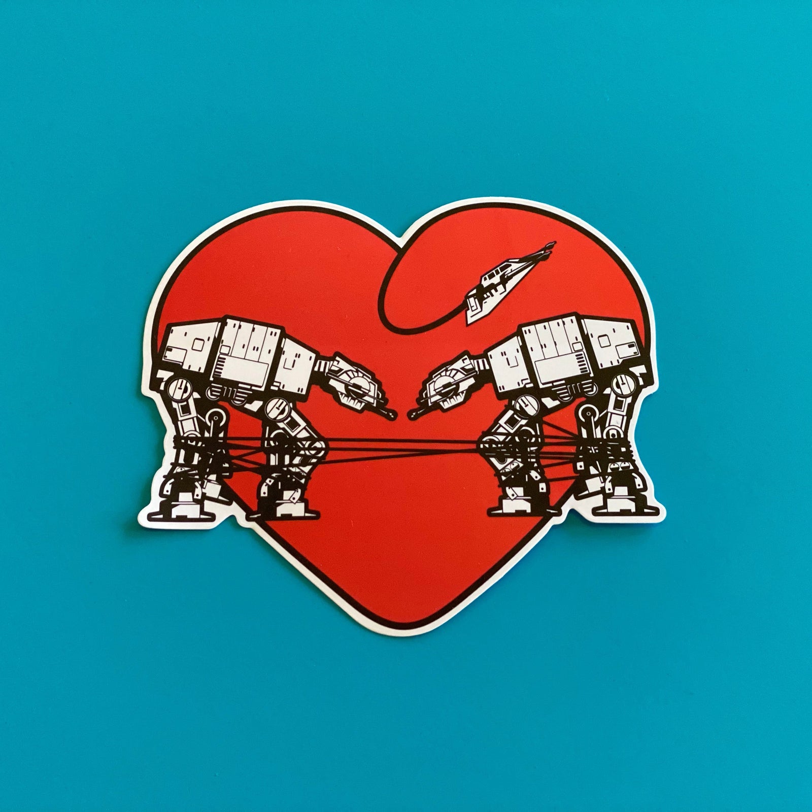 Red heart-shaped sticker with two robots on a blue background