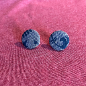 Blue patterned round earrings on a pink fabric background