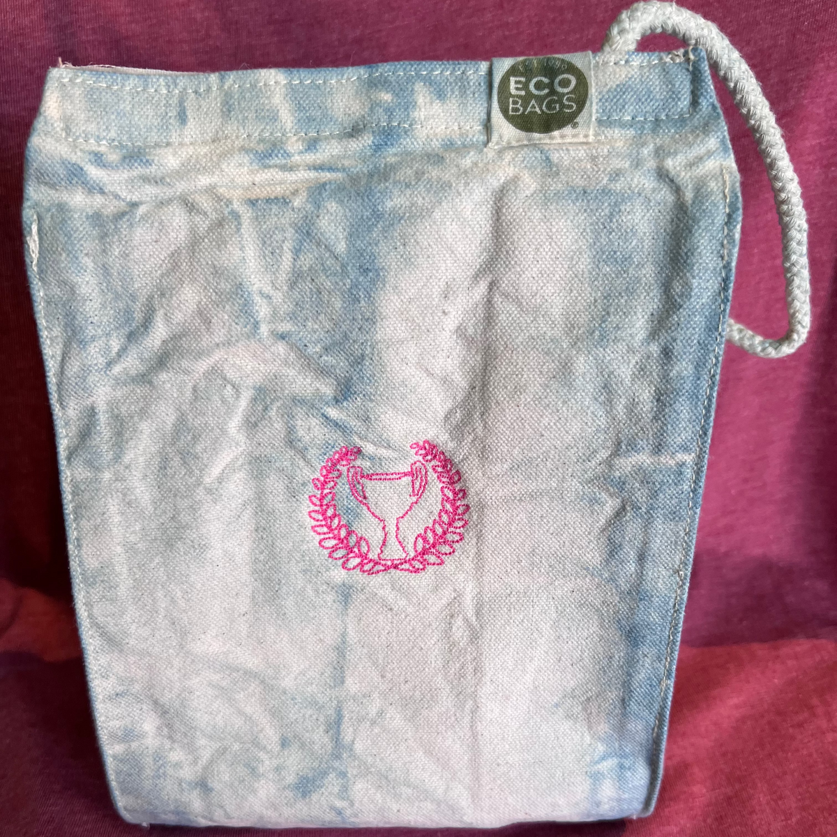 Indigo dyed lunch sack with pink embroidered trophy and laurels. 