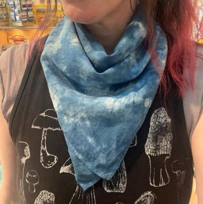 Person wearing a blue tie-dye bandana with a store in the background