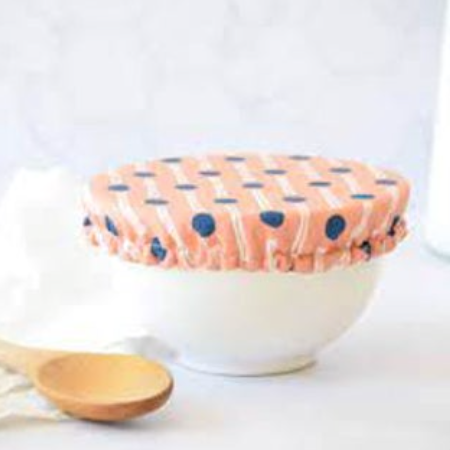 White bowl with a polka dot cover and wooden spoon on a white background