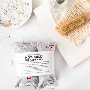 Hot and cold therapy pack with packaging on a marble surface with a wooden brush and bath salts.
