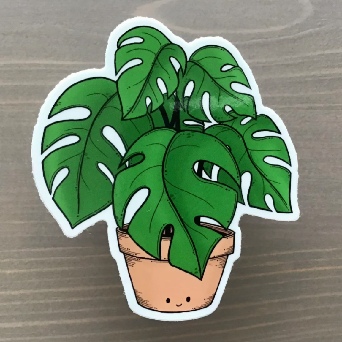 Cartoon-style potted plant sticker on a wooden surface