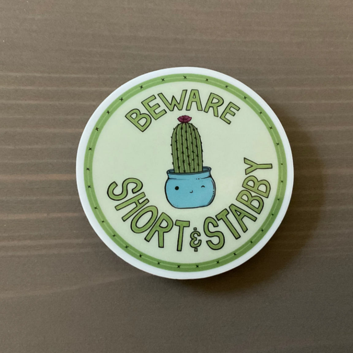 A round sticker with a cactus in a pot that says "Beware - short and stabby"