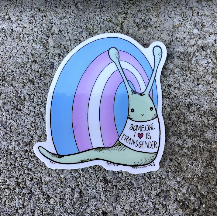 Sticker of a snail with a shell the colors of the transgender flag wearing a shirt that says "Someone I love is transgender"