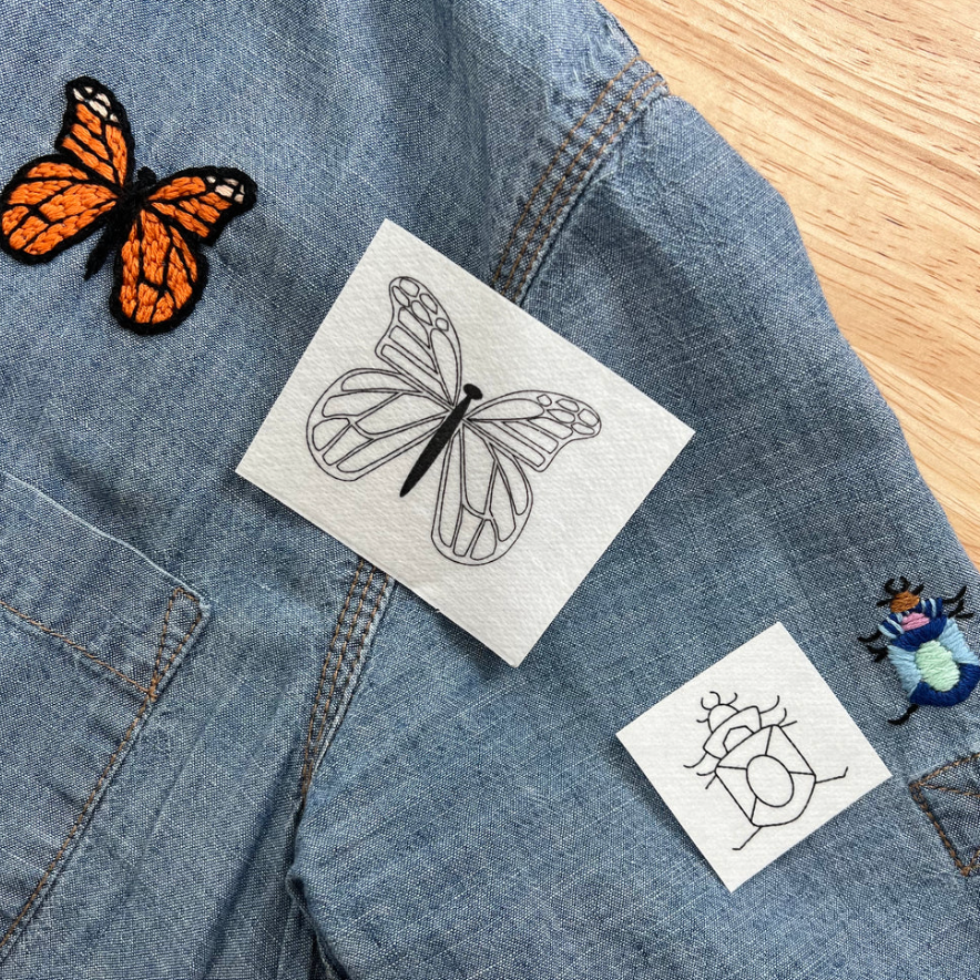 A butterfly and beetle embroidery sample on a denim shirt.