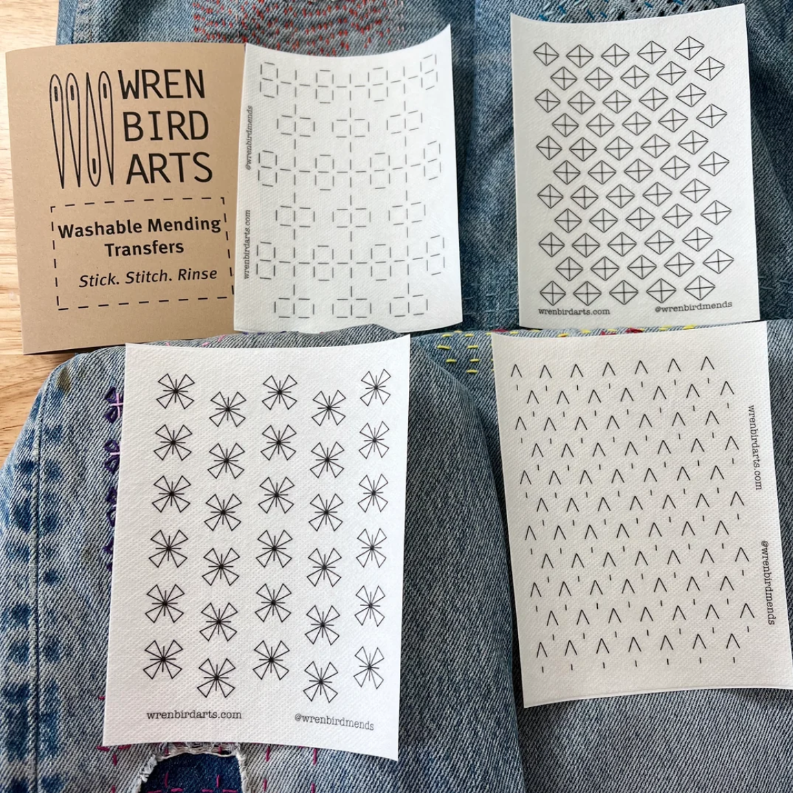 Four variations of washable mending transfers from Wren Bird Arts on top of denim fabric. 