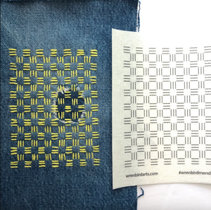 A close-up of a denim fabric sample with a yellow stitched grid pattern on the left, next to a white pattern card showing black stitched grid markings. The card has the website wrenbirdarts.