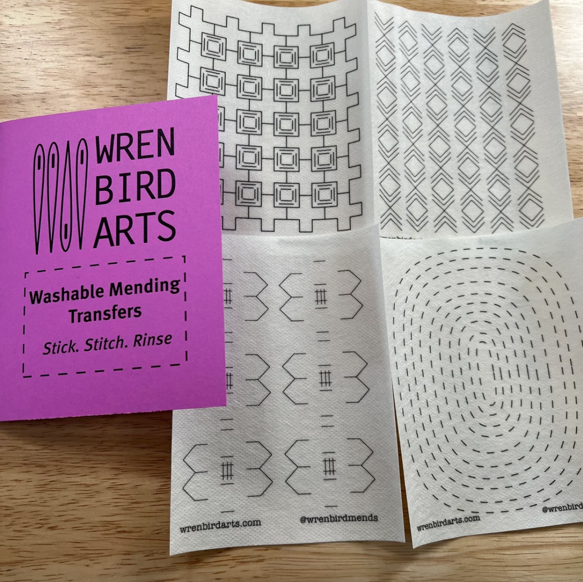Set of four washable mending transfers from Wren Bird Arts on a wooden surface. 