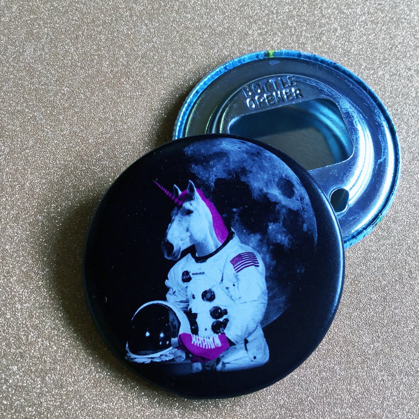 Bottle opener with unicorn astronaut design on a glittery surface. 