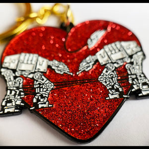 A red glittery keychain in the shape of a heart with an AT-AT from the Star Wars franchise design integrated into it.