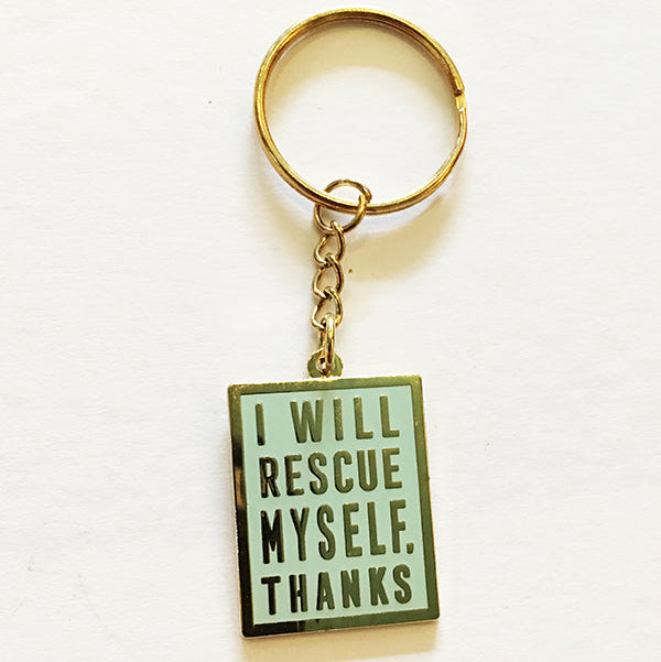 A mint colored keychain with gold hardware, a gold border, and gold lettering that says "I will rescue myself, thanks" against a white background. 